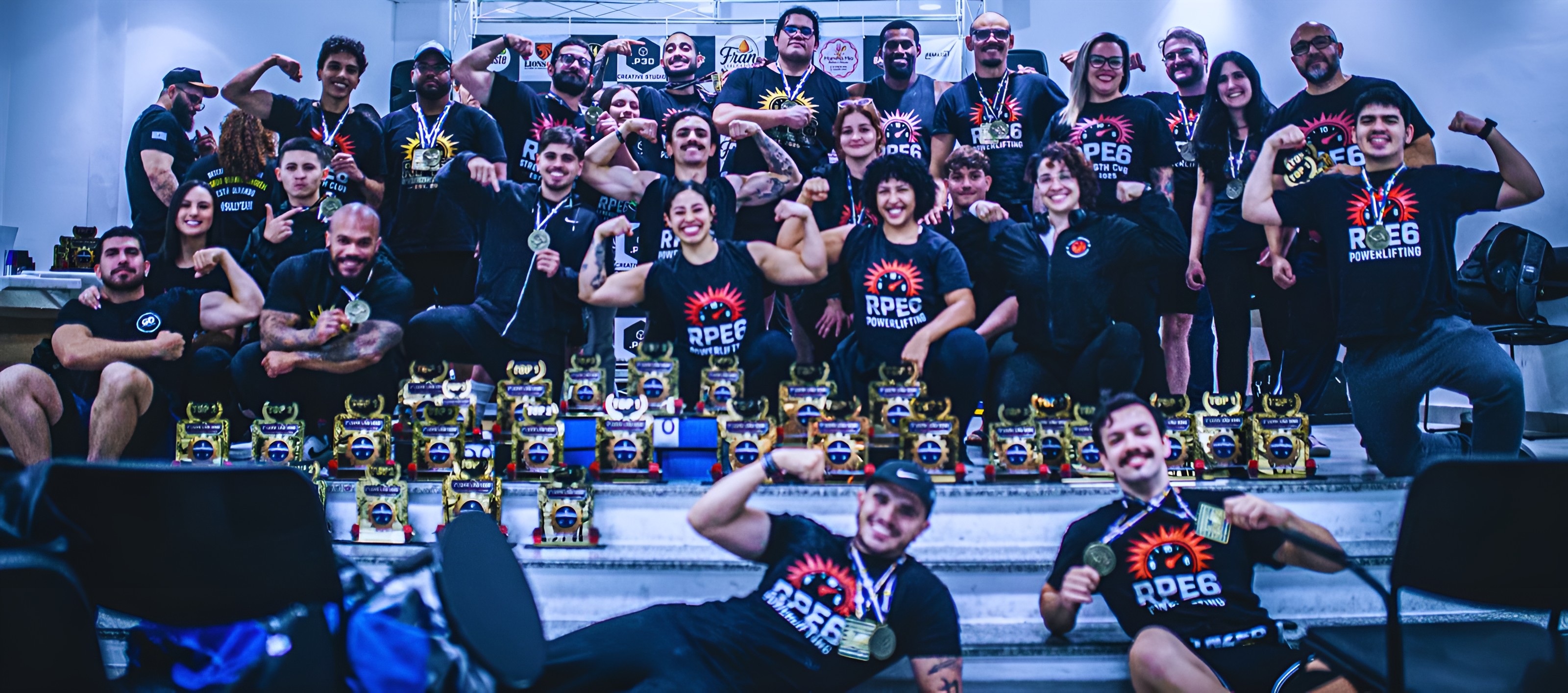 Atletas de powerlifting reunidos com medalhas e troféus